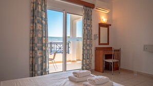 Une chambre d’hôtel avec un lit, un bureau, une chaise et un balcon offrant une vue.
