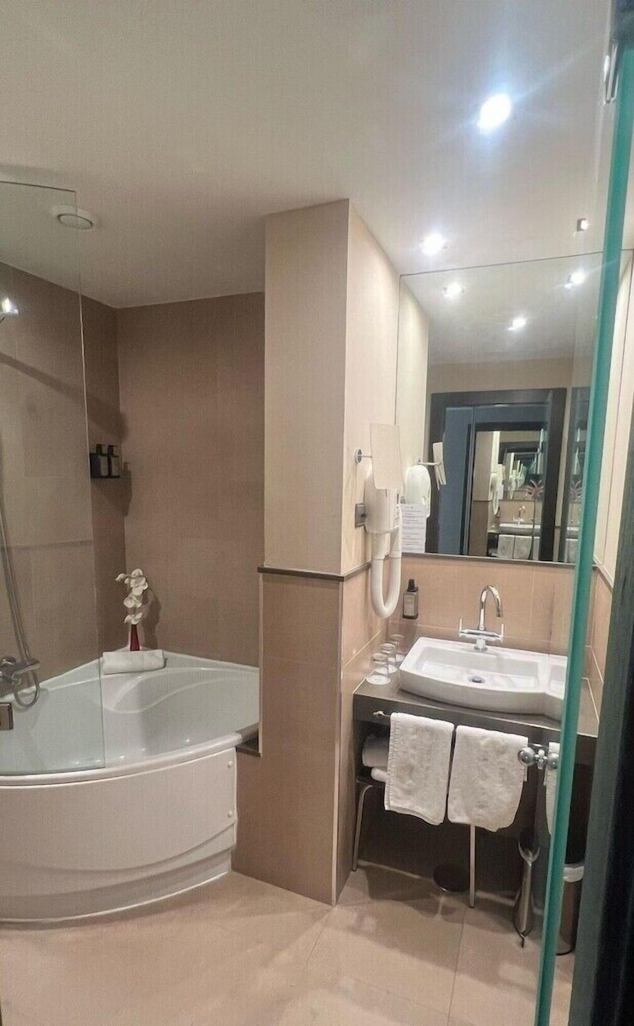 A modern bathroom with a bathtub, a sink, and a mirror.