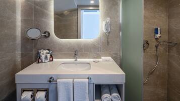 A modern bathroom with a large sink, mirror, towel rack, and a shower area.