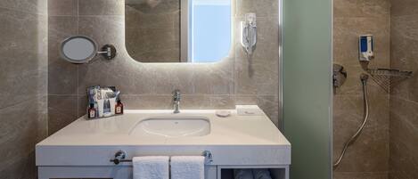 A modern bathroom with a large sink, mirror, towel rack, and a shower area.