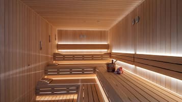 A sauna with wooden benches and benches, a wooden floor, and a wall-mounted heater.