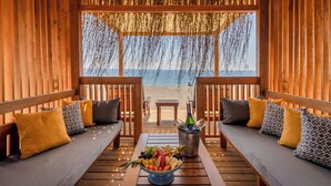 Eine Holzterrasse mit zwei Sofas und einem Tisch, einer Fruchtschale und einer Champagnerflasche.