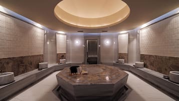 Bathroom features a central sink, two separate sinks, and a geometric pattern on the walls.