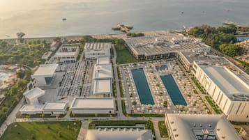 An aerial view of a resort with multiple buildings, a large swimming pool, and a marina.
