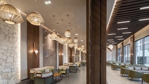 Eine moderne Hotellobby mit abgestuften Sitzgelegenheiten, Pendelleuchten und einer Wand aus Stein.
