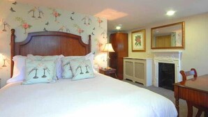 A bedroom with a large bed, a fireplace, a nightstand, and a wall-mounted mirror. - The Max Brighton (Brighton)