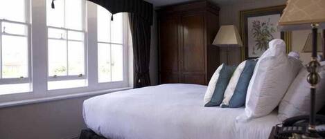 Una habitación de hotel con una cama grande, una ventana con cortinas, un armario de madera y una lámpara.