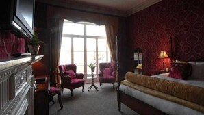A hotel room with a large bed, two armchairs, a fireplace, and a view of the outdoors. - The Max Brighton (Brighton)