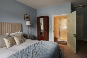 A bedroom with a bed, bedside table, lamp, and a wardrobe.
