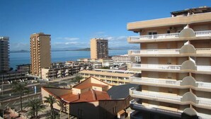 Paisatge urbà costaner amb edificis alts, cel blau clar i vista al mar.