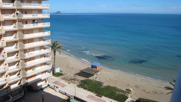 Un hotel davant de la platja amb múltiples balcons, una platja i una vista clara de l'oceà.