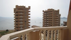 Un balcó amb vista a dos edificis alts i una massa d'aigua.