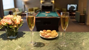 A pool table, two glasses of champagne, and a plate of macarons on a marble table. - Hôtel Montbriand Antony (Antony)