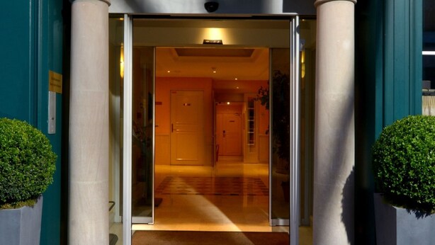 The entrance of Hotel Alixia with a glass door, columns, and a sign above. - Hôtel Montbriand Antony (Antony)