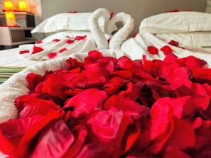 A bed with rose petals and swan-shaped pillows. - Hôtel Montbriand Antony (Antony)