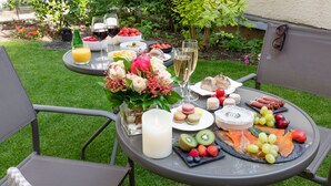 A round outdoor table set with food and drinks, surrounded by chairs. - Hôtel Montbriand Antony (Antony)