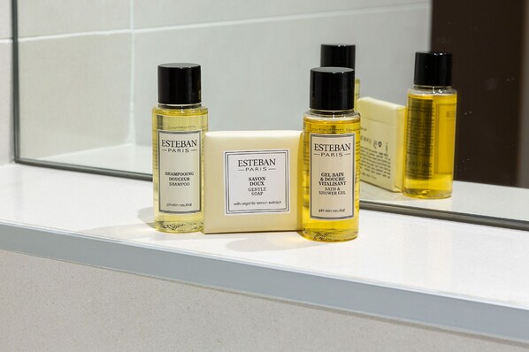 A bathroom shelf with Estéban Paris products including shampoo, soap, and shower gel.