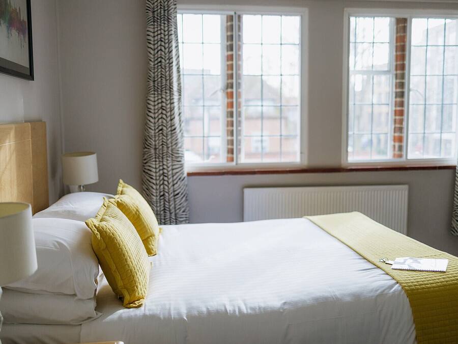 A hotel room with a large bed, two bedside lamps, and a window with curtains.