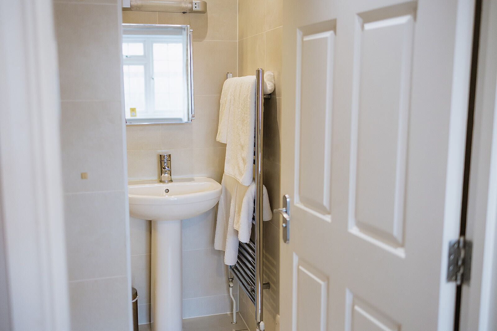 Une salle de bain avec un lavabo blanc, un miroir et un porte-serviettes.