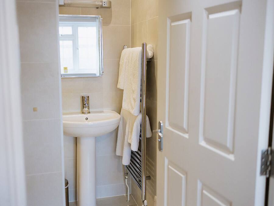 A bathroom with a white sink, a mirror, and a towel rack.