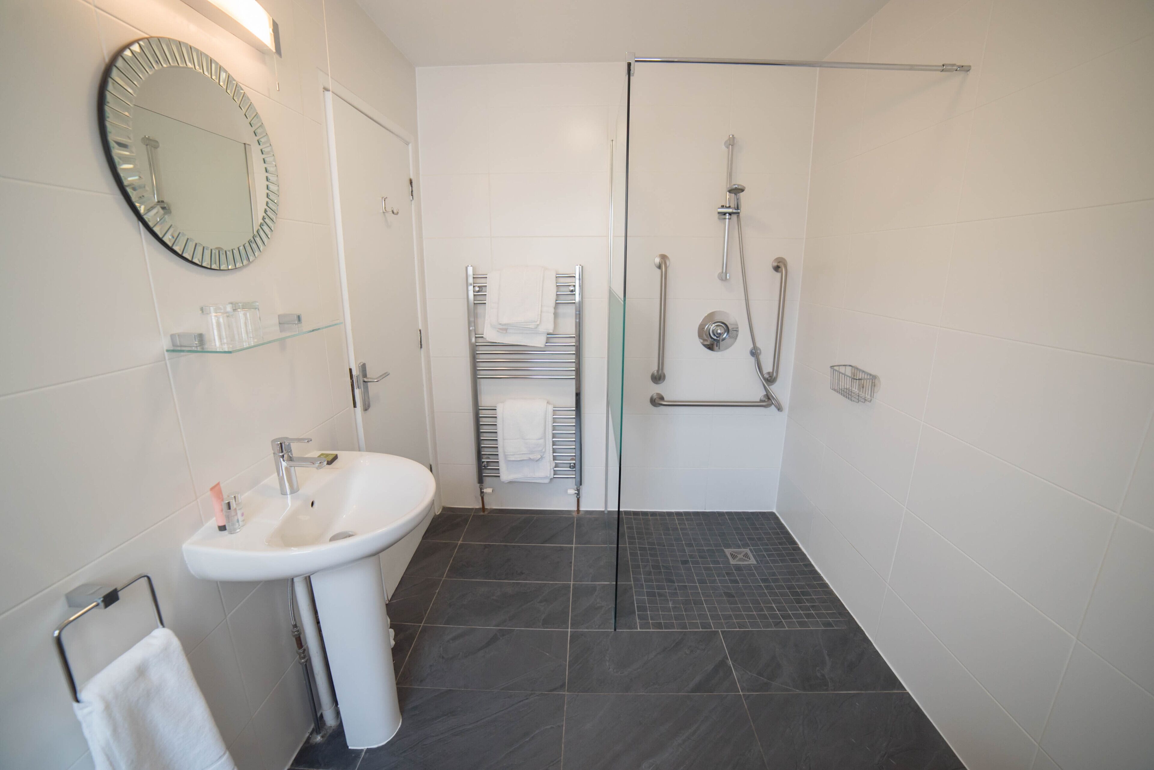 Un baño moderno con un lavamanos blanco, espejo y cabina de ducha de vidrio.