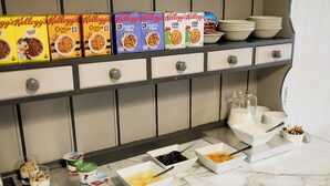 A breakfast buffet with various cereal boxes, bowls of yogurt, and other breakfast items on a marble countertop. - Red Mullions Guest House (Oxford)
