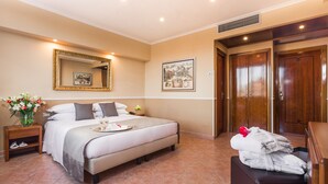 A hotel room with a large bed, a bedside table with a vase of flowers, a mirror, and a framed picture on the wall. - Raeli Hotel Lux (Rome)