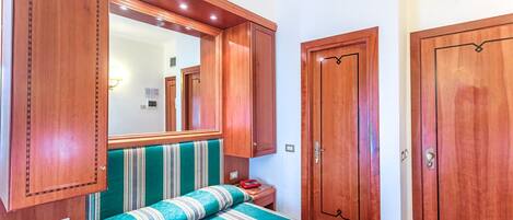 Un dormitorio con cama, armario de madera y espejo.