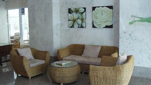 Un hall con un conjunto de sofá de mimbre, una mesa de centro y dos cuadros florales colgados en la pared.
