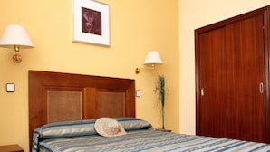 Ein Schlafzimmer mit einem Bett, zwei Nachttischlampen, einem gerahmten Bild an der Wand und einem Holzschrank.