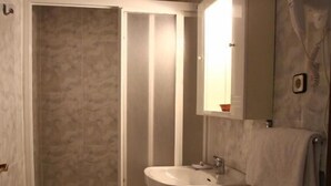 Ein Badezimmer mit Dusche, Waschbecken, Toilette und Spiegel.
