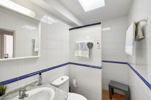 Bathroom features a sink, toilet, and shower area with a glass door.