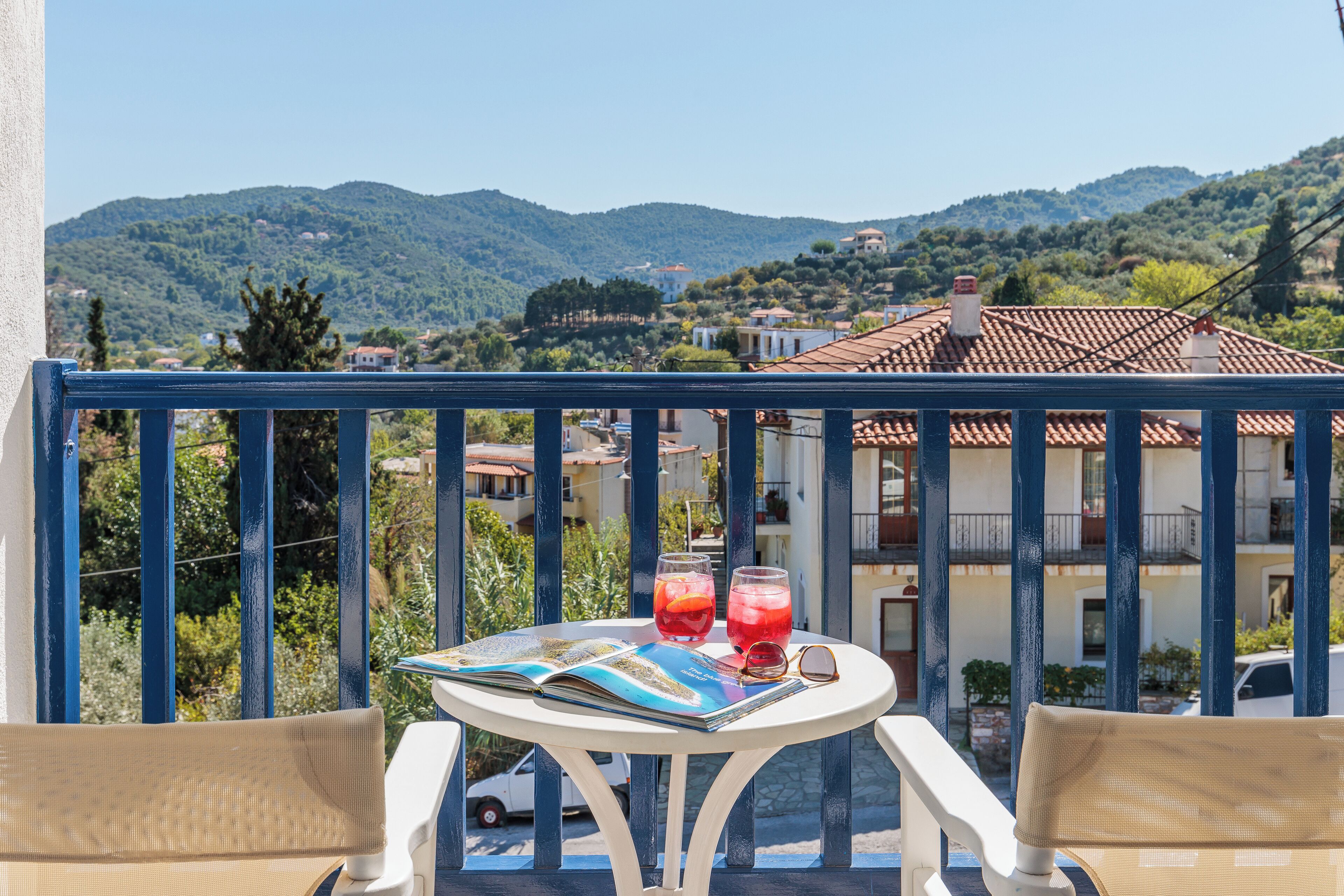 A balcony with a table, two chairs, and a view of a mountainous landscape.