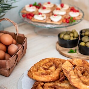 Une table garnie de pâtisseries, un panier d’œufs et des bols d’olives.