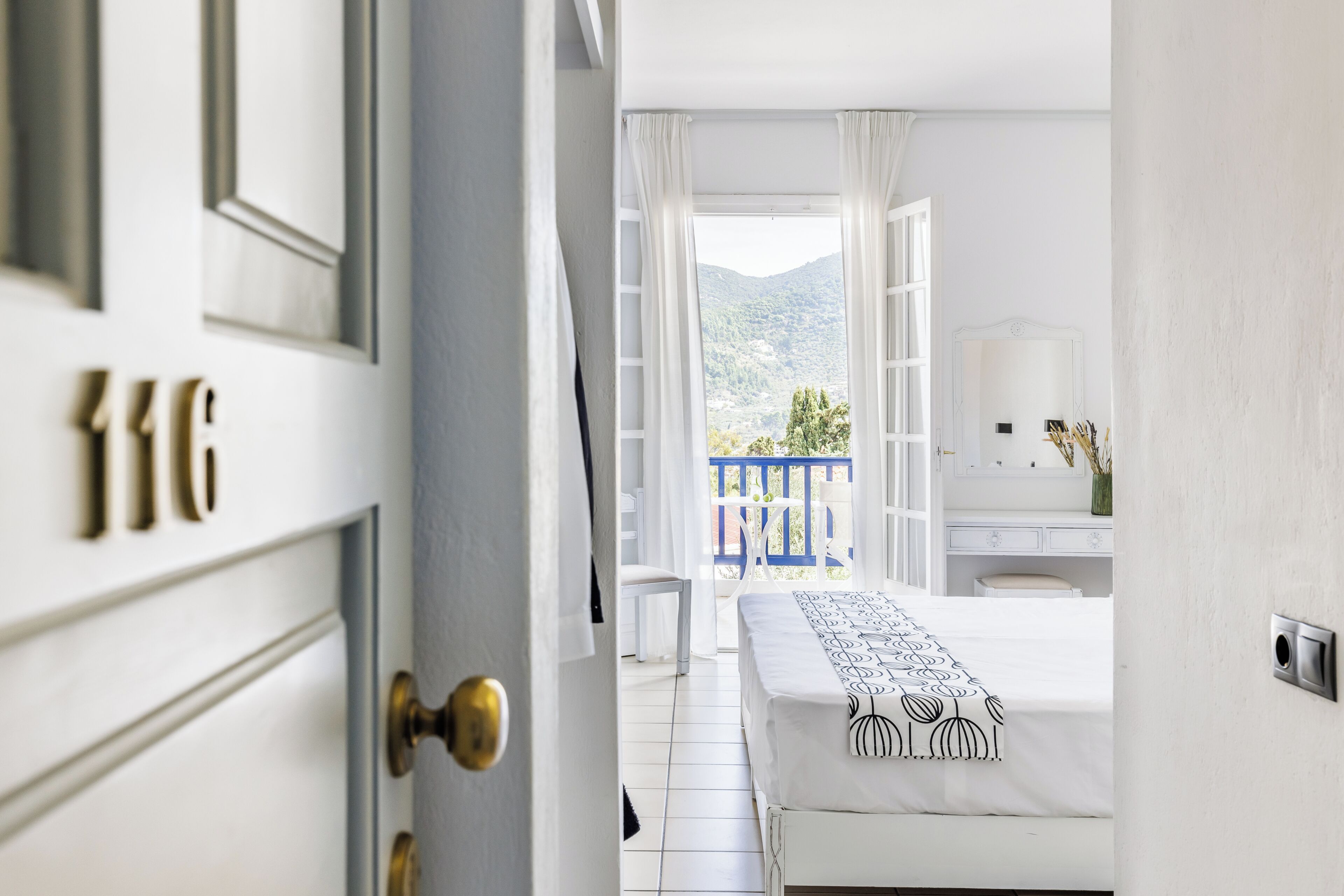 A hotel room with a bed, a desk, and a view of the mountains.