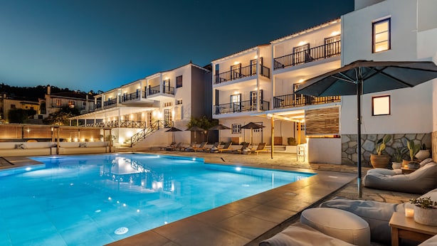A swimming pool with lounge chairs and a covered seating area, surrounded by multi-story buildings with balconies.