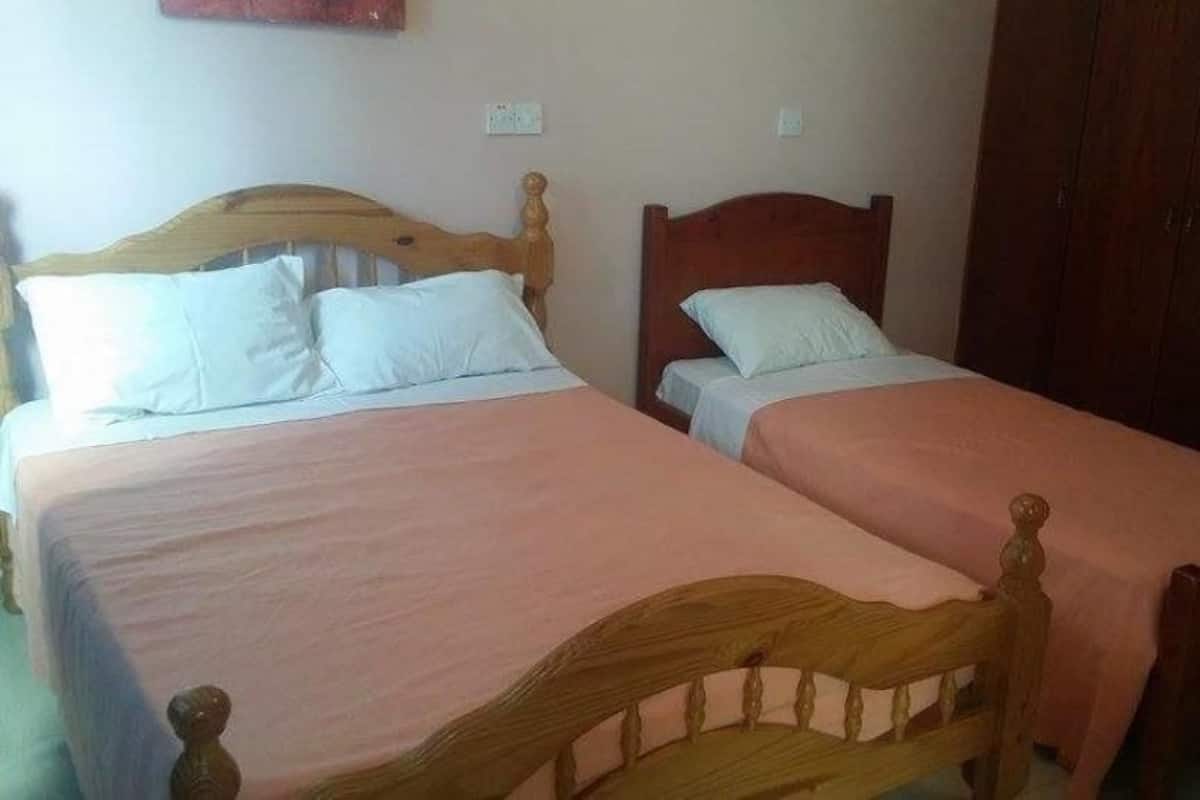 Two single beds with wooden headboards, a wardrobe, and a light-colored wall.