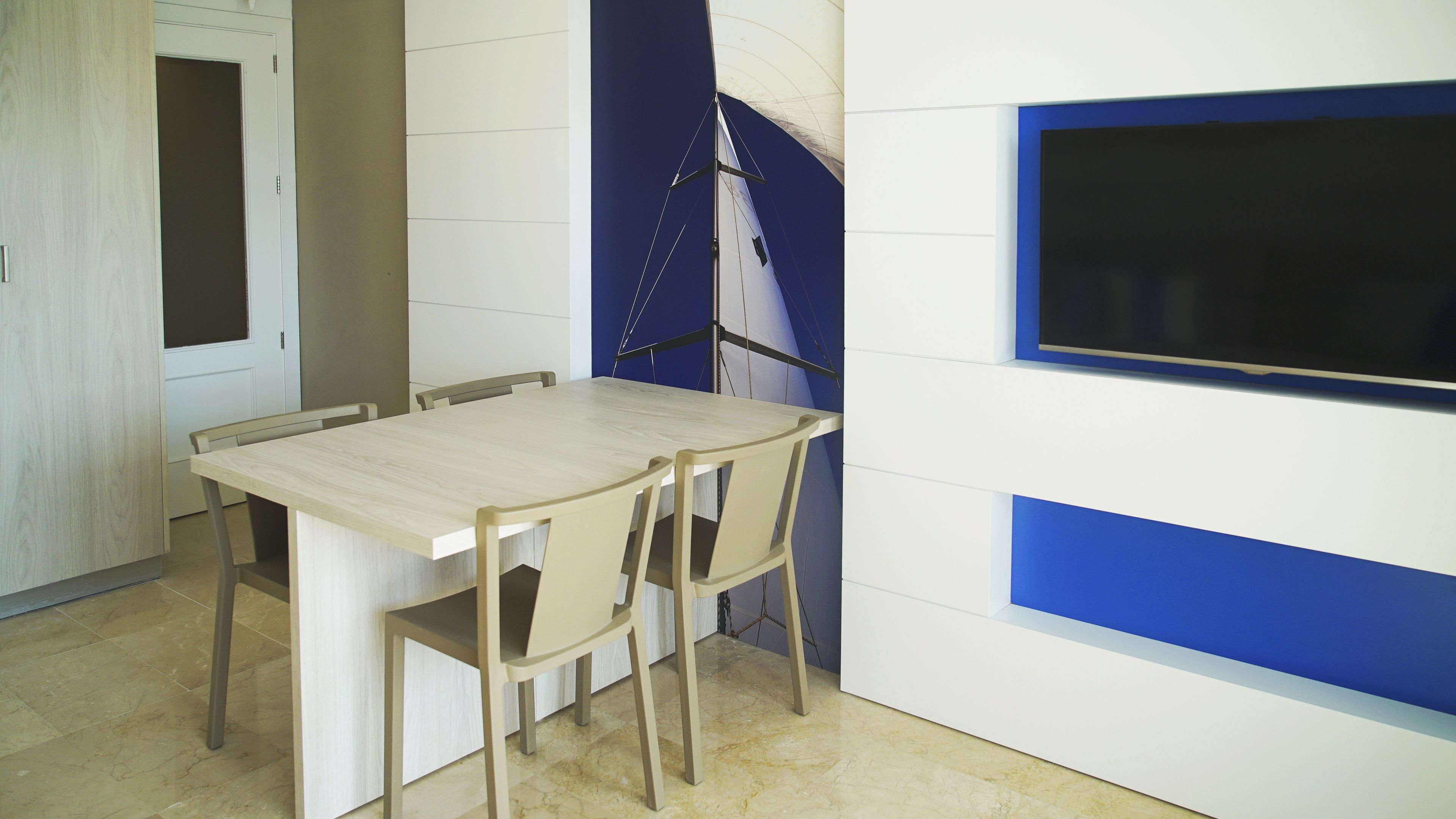Ein Essbereich mit Holztisch und -stühlen, einer weißen Wand mit blauer Akzentfarbe und einem großen Fenster.