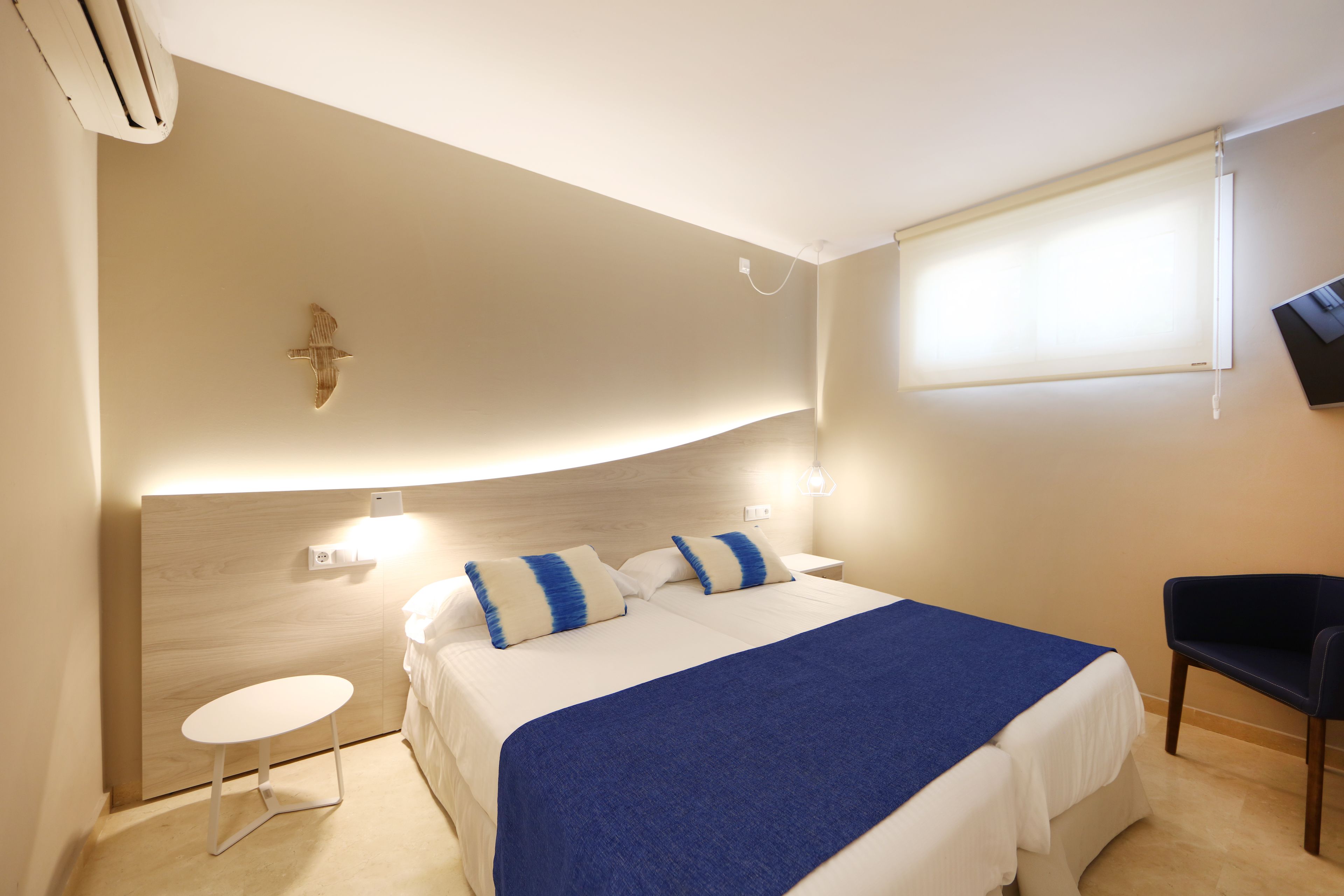 A hotel room with a bed, bedside table, and a chair.