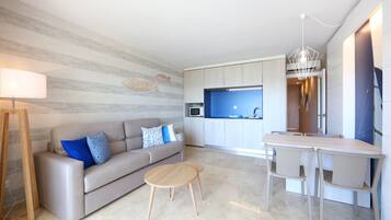 Un saló modern amb un sofà, una taula de centre i una zona de menjador amb cadires.