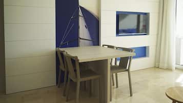 Een eetgedeelte met een houten tafel en stoelen, een blauwe accentmuur en een wandtelevisie.