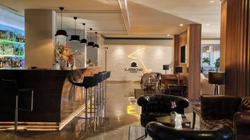 Un moderno bar con barra, varios taburetes y una zona de estar con sofás de cuero y una mesa de centro.