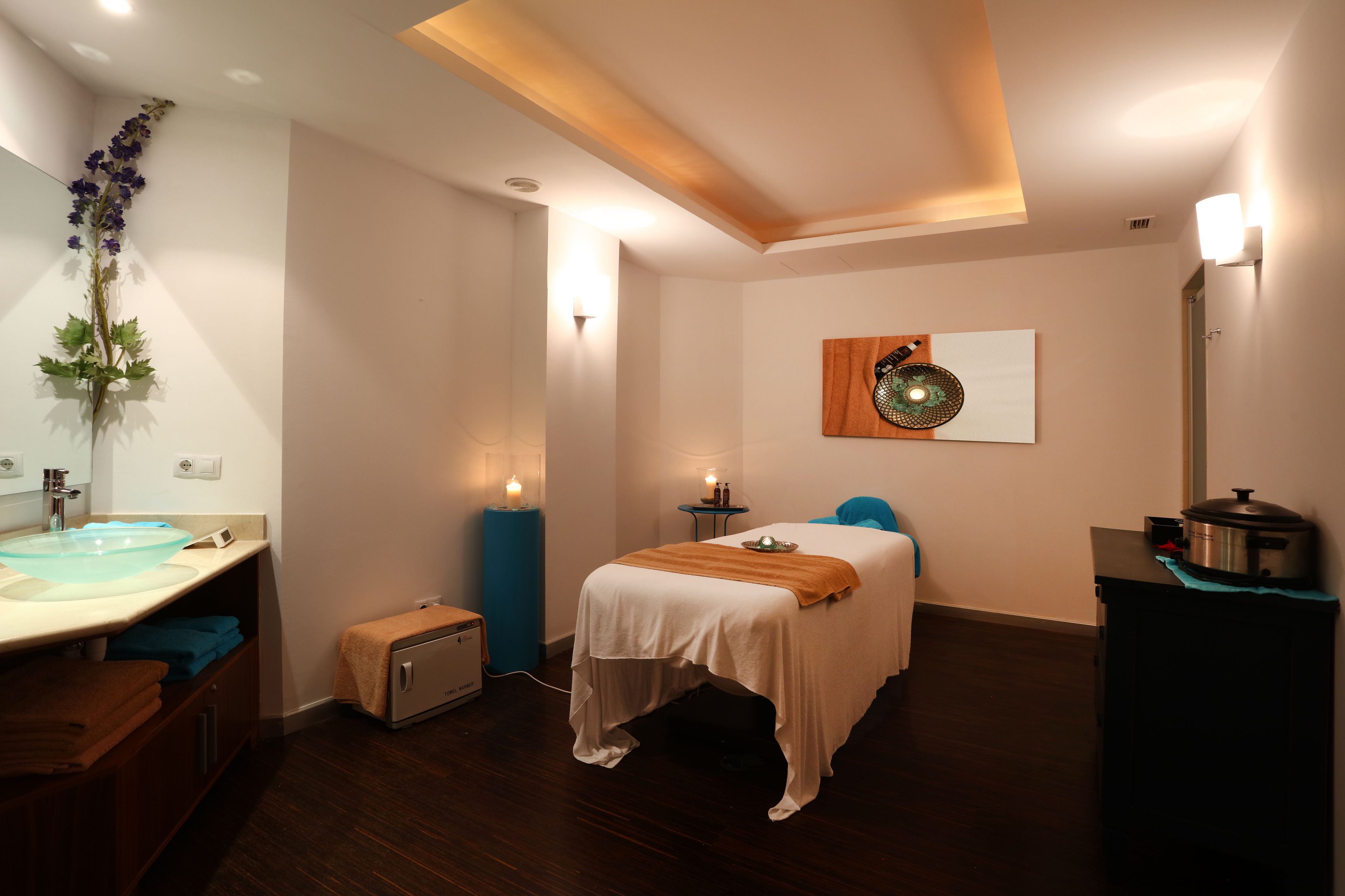 A modern bedroom with a bed, bedside table, and a small table with a lamp.