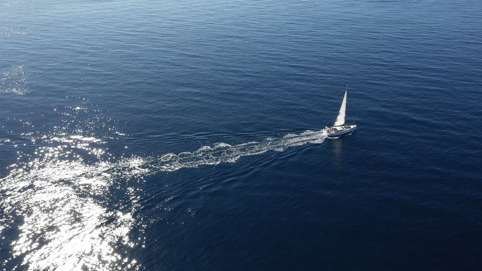Un velero en un mar tranquilo, con estela a su paso.