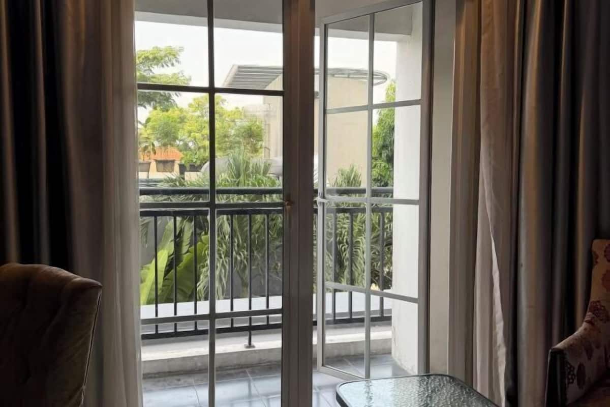 A room with a view of a balcony, a chair, and a table.