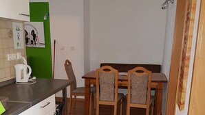 Uma cozinha compacta com espaço de refeições. Possui pia, chaleira e mesa de jantar com quatro cadeiras.