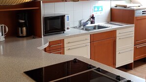 Uma cozinha moderna com ilha central, eletrodomésticos de aço inoxidável e uma janela grande sobre a pia.