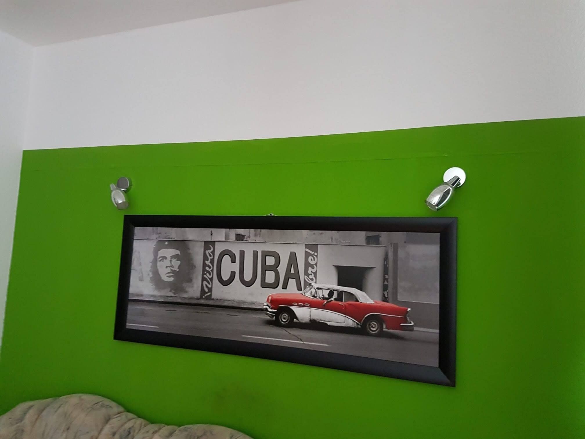 A framed picture of a red car with the word "CUBA" on a green wall.