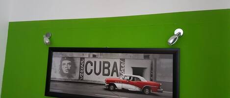 A framed picture of a red car with the word "CUBA" on a green wall.