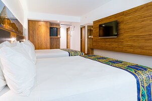 A hotel room with a large bed, a TV mounted on the wall, and wooden paneling.